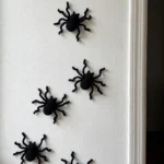 Small crocheted spiders climbing up a white wall