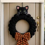 Black cat Halloween wreath with striped bow on front door