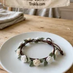 Winter white camellia crochet bracelet with green leaves on a leather cord